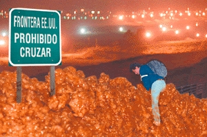 A Mexican attempts to jump over the 15-foot-high wall of beef guarding the U.S. border. Minutes after this photo was taken, the man was captured and returned to Mexico, unsuccessful but fully satiated.